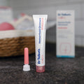 A tube of Dr. Talbot’s Mom Pregnancy & Postpartum Hemorrhoid Ointment with a pink cap, a separate pink applicator tip, and the product box in the background.