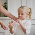 A young girl holds a Dr. Talbot’s Sure-Dose™ Medicine Syringe to her mouth while an adult assists with an accurate dosage.