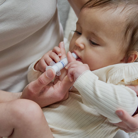 An adult uses a small oral syringe to administer Dr. Talbot’s Infant Pain + Fever Relief to a baby.