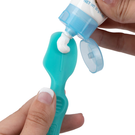 Someone applies diaper cream using Dr. Talbot's Mini Diaper Cream Soft Silicone Brush, holding the tube and the blue brush—just like squeezing white toothpaste onto a toothbrush to gently protect a baby's delicate skin.